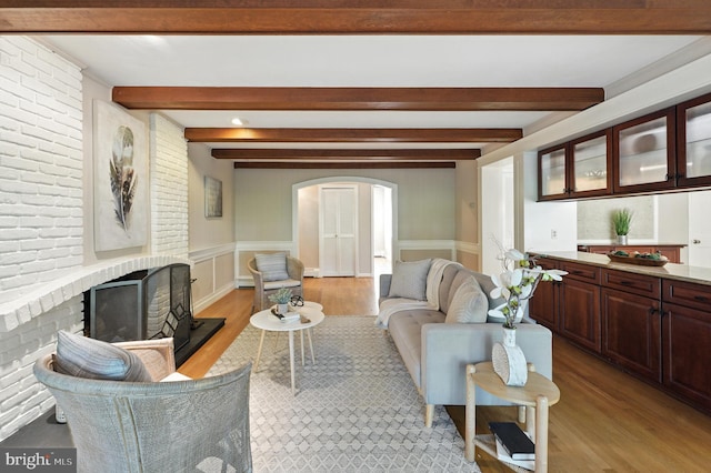 508 Vierling Dr, Silver Spring, MD 20904 - living room with arched walkways, light wood-style flooring, beamed ceiling, wainscoting, and a brick fireplace
