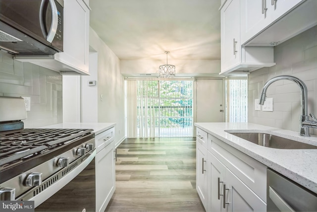 4939 Americana Dr Unit 106, Annandale, VA 22003 - kitchen with appliances with stainless steel finishes, white cabinetry, backsplash, light wood-style flooring, and light stone counters