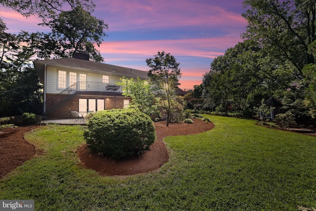 906 Danton Ln, Alexandria, VA 22308 - back of property at dusk featuring a patio, stairs, a lawn, brick siding, and a chimney