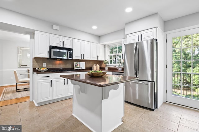 906 Danton Ln, Alexandria, VA 22308 - kitchen featuring stainless steel appliances, dark countertops, a center island, white cabinets, and tasteful backsplash