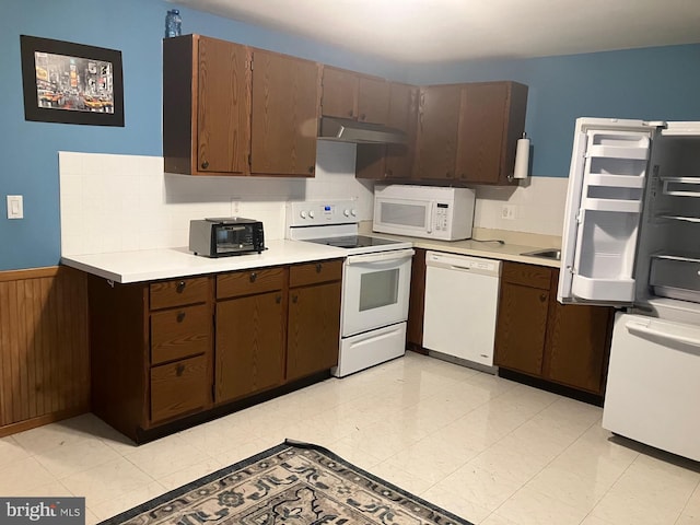 18327 Ivy Oak Ter, Gaithersburg, MD 20877 - kitchen featuring white appliances, under cabinet range hood, light countertops, backsplash, and a wainscoted wall