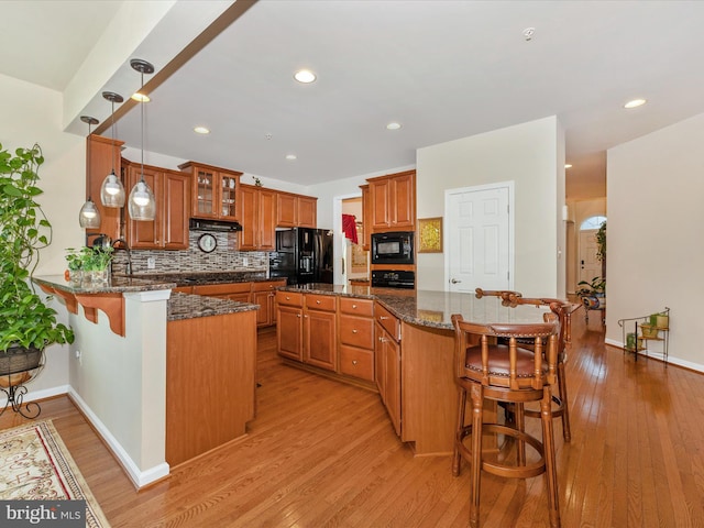 9175 Bealls Farm Rd, Frederick, MD 21704 - kitchen with black appliances, a kitchen breakfast bar, brown cabinetry, backsplash, and dark stone countertops