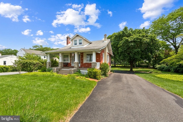 615 Convent Rd, Aston, PA 19014 - bungalow-style home with covered porch, a chimney, driveway, a front lawn, and brick siding
