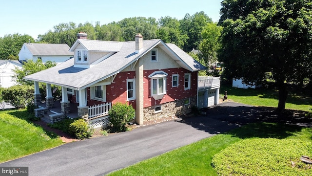 615 Convent Rd, Aston, PA 19014 - view of front facade featuring a porch, a chimney, asphalt driveway, a front yard, and a garage