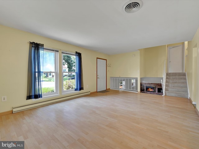 171 Tanglewood Ln, Lancaster, PA 17601 - unfurnished living room featuring a baseboard heating unit, light wood-style floors, a lit fireplace, and stairway
