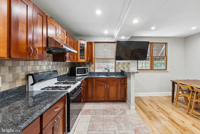 2847 S 65th St, Philadelphia, PA 19142 - kitchen with range with gas cooktop, under cabinet range hood, stainless steel microwave, tasteful backsplash, and dark stone counters