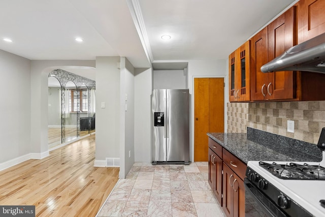 2847 S 65th St, Philadelphia, PA 19142 - kitchen with stainless steel refrigerator with ice dispenser, white range with gas cooktop, exhaust hood, arched walkways, and backsplash