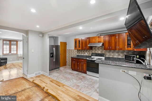 2847 S 65th St, Philadelphia, PA 19142 - kitchen featuring appliances with stainless steel finishes, under cabinet range hood, arched walkways, glass insert cabinets, and recessed lighting