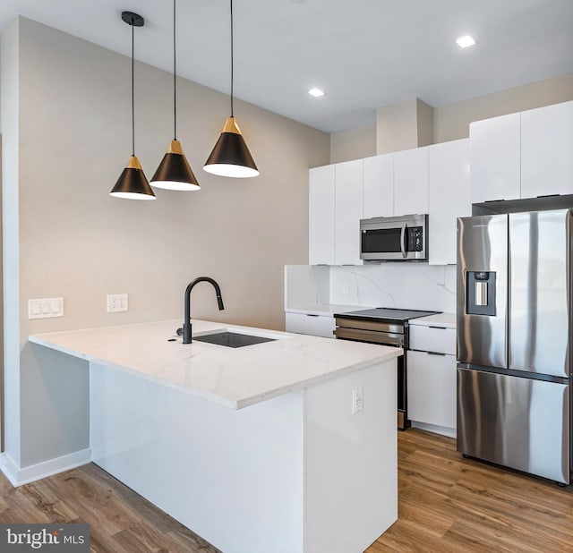 1358 Florida Ave NE Unit Ph-02, Washington, DC 20002 - kitchen featuring stainless steel appliances, wood finished floors, a peninsula, white cabinetry, and pendant lighting