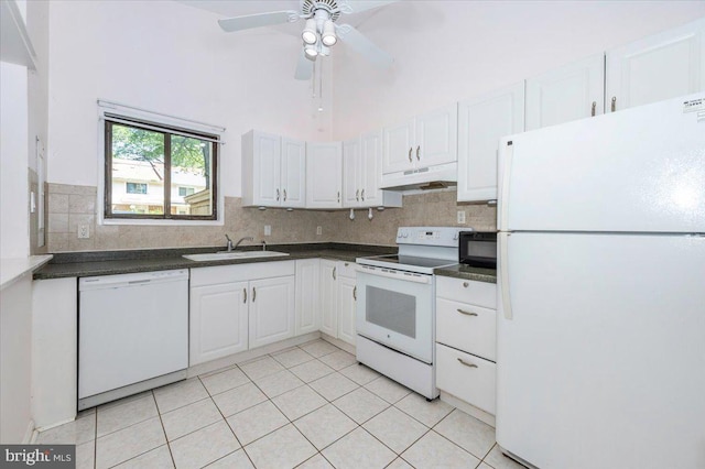 18503 Nutmeg Pl, Germantown, MD 20874 - kitchen featuring white appliances, under cabinet range hood, dark countertops, light tile patterned floors, and a towering ceiling