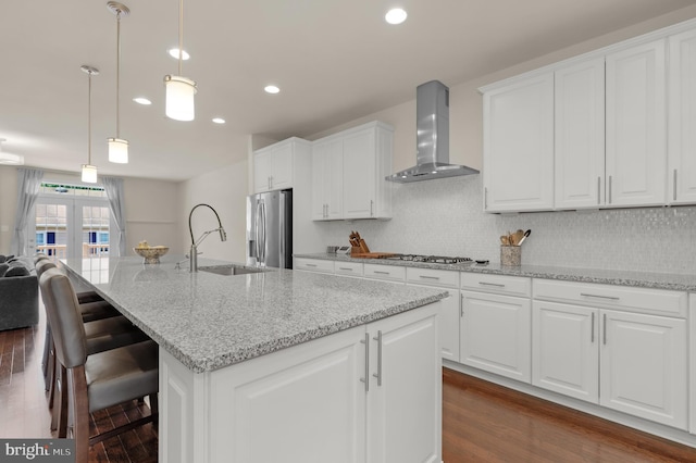 1025 Mutual Pl, Sandy Spring, MD 20860 - kitchen featuring wall chimney exhaust hood, stainless steel appliances, dark wood finished floors, a center island with sink, and white cabinetry