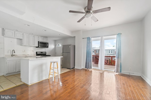 1816 Chilton St, Baltimore, MD 21218 - kitchen featuring stainless steel appliances, light wood-style flooring, light countertops, a ceiling fan, and a kitchen island