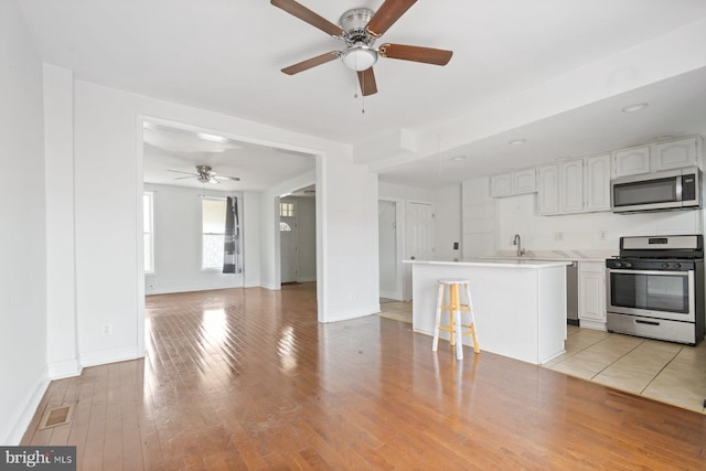 1816 Chilton St, Baltimore, MD 21218 - kitchen featuring appliances with stainless steel finishes, ceiling fan, white cabinetry, and light wood-type flooring