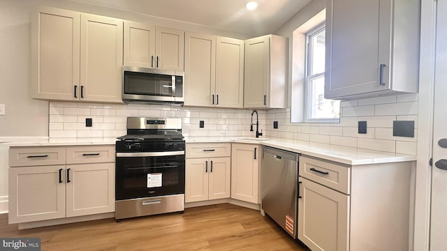 5841 Cedarhurst St, Philadelphia, PA 19143 - kitchen with appliances with stainless steel finishes, light wood finished floors, decorative backsplash, light stone counters, and recessed lighting