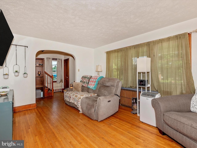 21127 Twin Springs Dr, Smithsburg, MD 21783 - living area with arched walkways, light wood-type flooring, radiator heating unit, a textured ceiling, and radiator