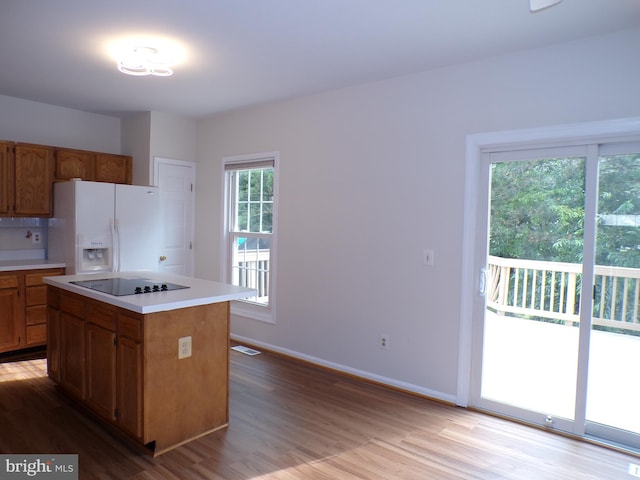 44035 Kings Arms Sq, Ashburn, VA 20147 - kitchen featuring white fridge with ice dispenser, black electric cooktop, light wood-style flooring, light countertops, and brown cabinets