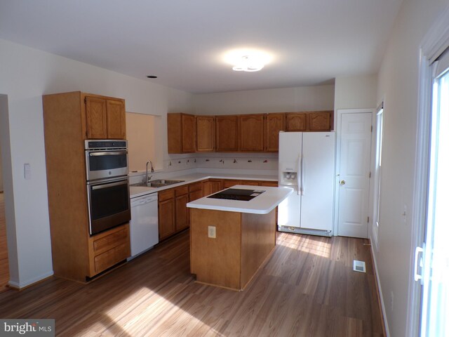 44035 Kings Arms Sq, Ashburn, VA 20147 - kitchen featuring white appliances, wood finished floors, a kitchen island, light countertops, and brown cabinetry