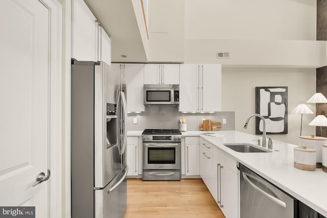 2431 Ontario Rd NW Unit 4, Washington, DC 20009 - kitchen featuring stainless steel appliances, light wood-type flooring, light countertops, white cabinets, and decorative backsplash