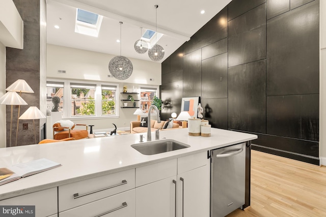 2431 Ontario Rd NW Unit 4, Washington, DC 20009 - kitchen with a towering ceiling, stainless steel dishwasher, light countertops, light wood finished floors, and pendant lighting