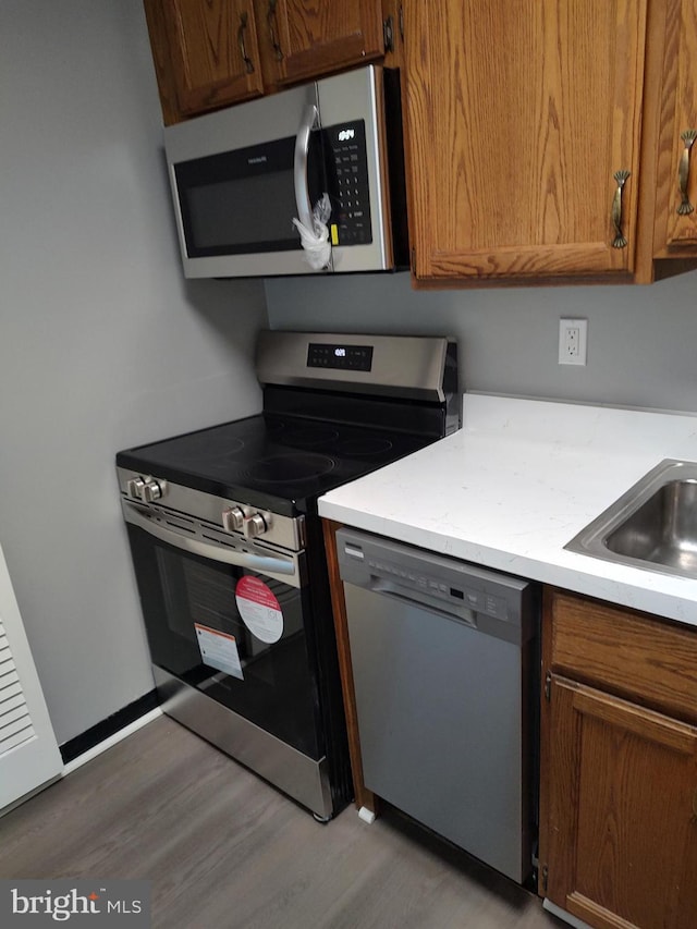 1301 Delaware Ave SW Unit N103, Washington, DC 20024 - kitchen with appliances with stainless steel finishes, light wood finished floors, and brown cabinets