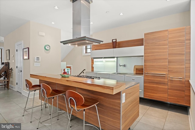 9 E Walnut St, Alexandria, VA 22301 - kitchen with island range hood, modern cabinets, light tile patterned floors, a kitchen bar, and stainless steel gas stovetop