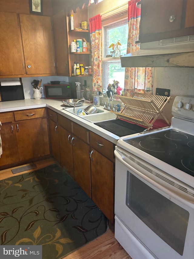 23069 Raleigh Rd, Chestertown, MD 21620 - kitchen with white range with electric cooktop, ventilation hood, black microwave, light countertops, and brown cabinetry