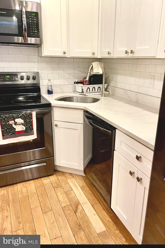 2538 N 16th St, Philadelphia, PA 19132 - kitchen featuring appliances with stainless steel finishes, white cabinets, light wood-style floors, light countertops, and decorative backsplash