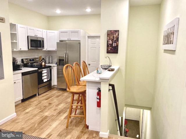 2538 N 16th St, Philadelphia, PA 19132 - kitchen featuring appliances with stainless steel finishes, tasteful backsplash, light wood-style floors, a kitchen bar, and light countertops