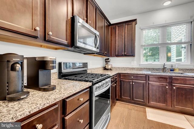 8321 Meadowood Dr, Hanover, MD 21076 - kitchen featuring appliances with stainless steel finishes, light stone counters, light wood-type flooring, dark brown cabinetry, and recessed lighting