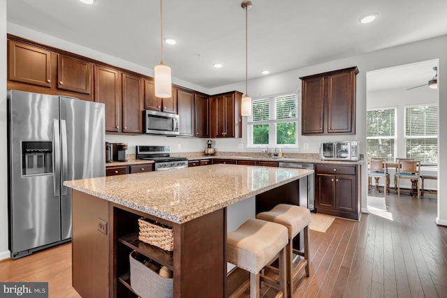 8321 Meadowood Dr, Hanover, MD 21076 - kitchen featuring appliances with stainless steel finishes, open shelves, a kitchen island, light stone countertops, and pendant lighting