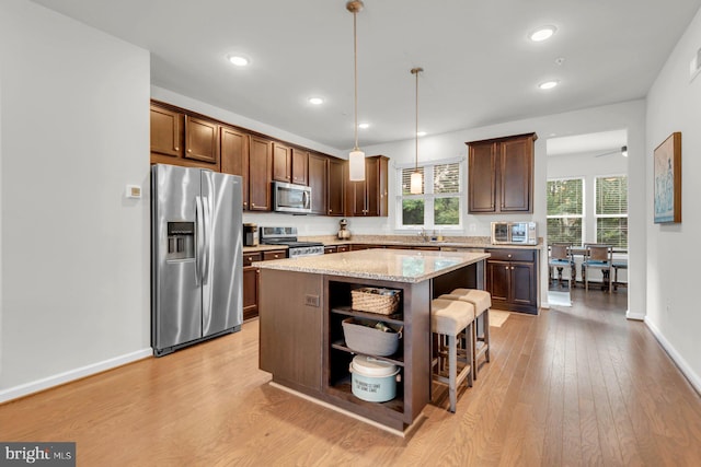 8321 Meadowood Dr, Hanover, MD 21076 - kitchen featuring appliances with stainless steel finishes, open shelves, a breakfast bar, light wood-style floors, and a kitchen island