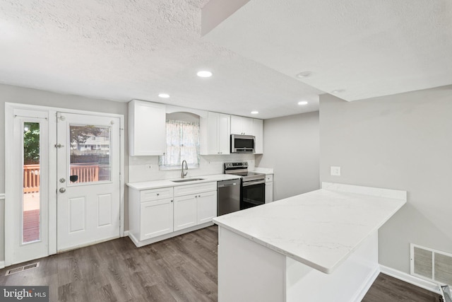 9228 Pinenut Ct, Laurel, MD 20723 - kitchen with appliances with stainless steel finishes, white cabinetry, a textured ceiling, a peninsula, and dark wood-style flooring