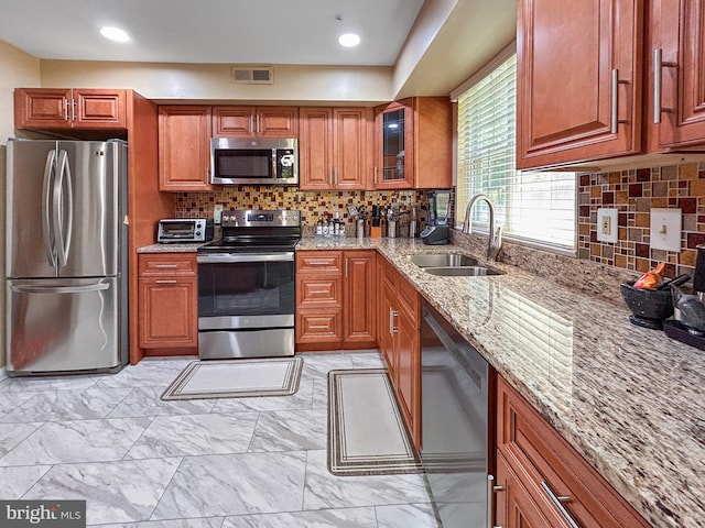 907 Dunloring Ct, Upper Marlboro, MD 20774 - kitchen featuring appliances with stainless steel finishes, light stone countertops, brown cabinetry, backsplash, and recessed lighting