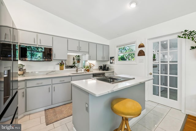 2307 Sherwood Hall Ln, Alexandria, VA 22306 - kitchen with stainless steel microwave, gray cabinets, lofted ceiling, a kitchen bar, and a center island
