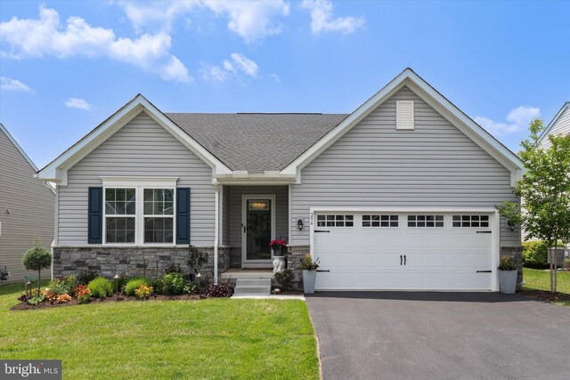 294 Letitia Manor Dr, West Grove, PA 19390 - view of front facade with driveway, stone siding, a front yard, a shingled roof, and an attached garage