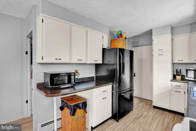 1124 Fairview Dr, Reading, PA 19605 - kitchen featuring baseboard heating, freestanding refrigerator, stainless steel microwave, a textured ceiling, and light wood-type flooring