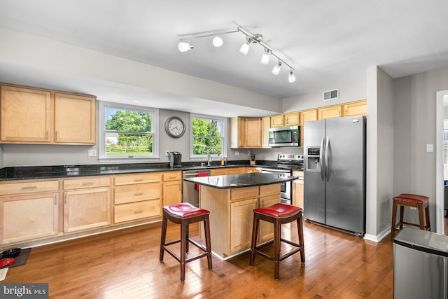 15321 Peach Orchard Rd, Silver Spring, MD 20905 - kitchen with appliances with stainless steel finishes, light brown cabinetry, a breakfast bar, hardwood / wood-style flooring, and dark countertops