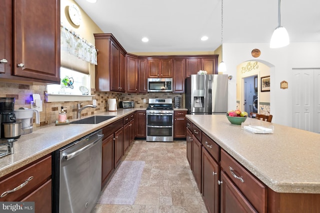 231 Lupine Dr, Smyrna, DE 19977 - kitchen with appliances with stainless steel finishes, tasteful backsplash, arched walkways, a kitchen island, and light stone finish floors