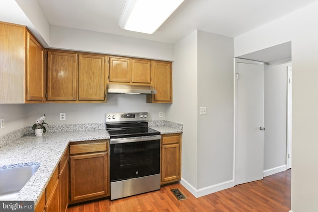 7547 Filbert Ter, Gaithersburg, MD 20879 - kitchen featuring stainless steel electric range oven, under cabinet range hood, wood finished floors, and brown cabinets