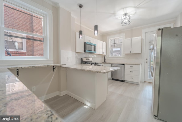 3335 Dudley Ave, Baltimore, MD 21213 - kitchen featuring appliances with stainless steel finishes, a peninsula, light wood-style floors, white cabinets, and ornamental molding
