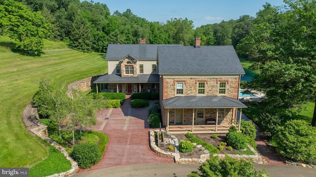 5751 Mount Pisgah Rd, York, PA 17406 - view of front of home with covered porch, stone siding, a chimney, a front yard, and a forest view