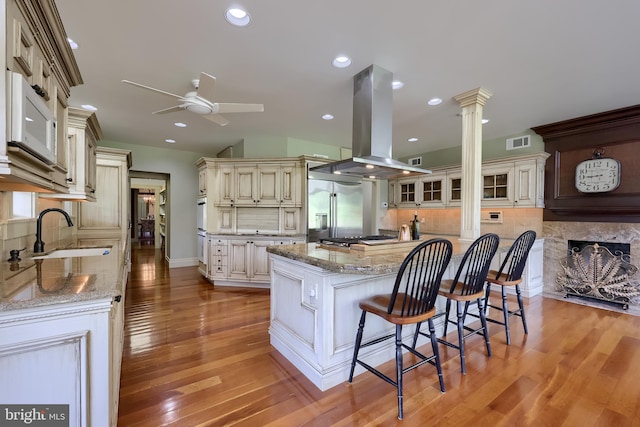 5751 Mount Pisgah Rd, York, PA 17406 - kitchen featuring island range hood, ceiling fan, ornate columns, cream cabinets, and stainless steel appliances