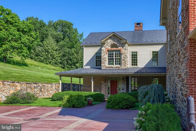 5751 Mount Pisgah Rd, York, PA 17406 - view of front of house with stone siding, a chimney, a porch, and a high end roof