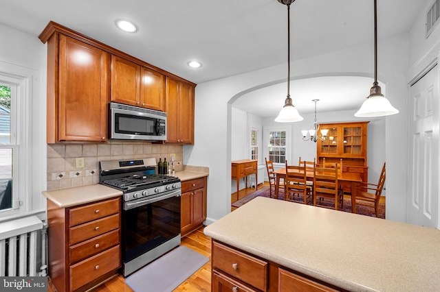 206 E Lake Ave, Baltimore, MD 21212 - kitchen featuring appliances with stainless steel finishes, backsplash, arched walkways, brown cabinetry, and light countertops