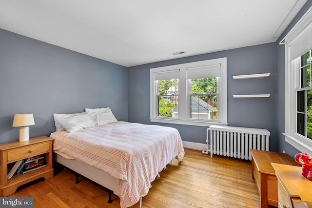 206 E Lake Ave, Baltimore, MD 21212 - bedroom with radiator, multiple windows, and light wood-type flooring