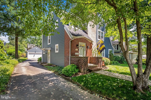 206 E Lake Ave, Baltimore, MD 21212 - view of front facade featuring brick siding, an outbuilding, a front lawn, a garage, and a shingled roof