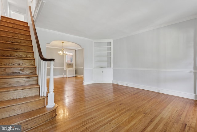 7527 Germantown Ave, Philadelphia, PA 19119 - unfurnished living room with arched walkways, built in shelves, wood finished floors, stairs, and crown molding