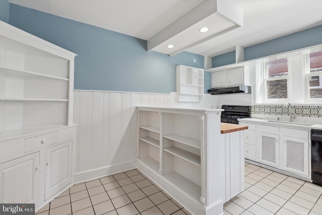 7527 Germantown Ave, Philadelphia, PA 19119 - kitchen featuring open shelves, black range with electric stovetop, under cabinet range hood, light tile patterned floors, and a wainscoted wall