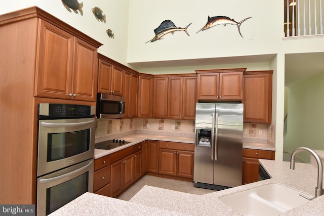 36765 Hummingbird Way N, Selbyville, DE 19975 - kitchen featuring appliances with stainless steel finishes, light countertops, decorative backsplash, brown cabinets, and a high ceiling