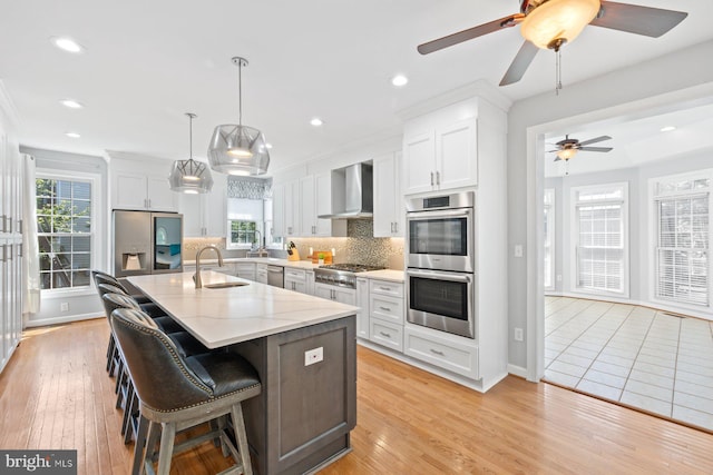 20736 Ashburn Station Pl, Ashburn, VA 20147 - kitchen with appliances with stainless steel finishes, wall chimney exhaust hood, backsplash, a ceiling fan, and a center island with sink